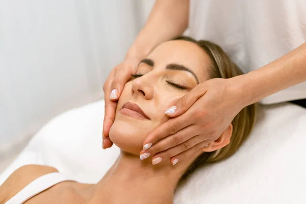 Mujer de mediana edad que tiene un masaje en la cabeza en un salón de belleza. — Foto de Stock