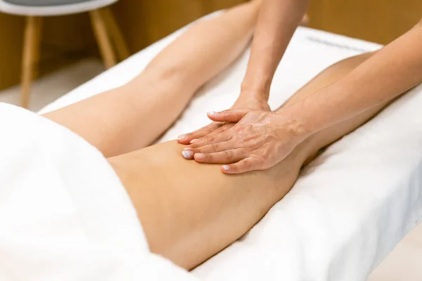 Beauty salon professional pouring oil from a massage candle on the back of his patient. — Stock Photo, Image