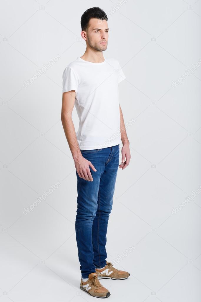Serious young man standing against white background 