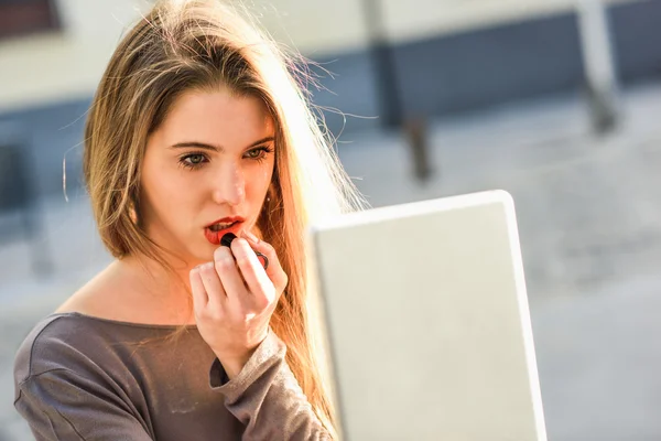 Jovem mulher aplicando batom olhando para tablet — Fotografia de Stock