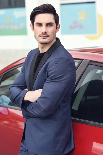 Ελκυστική νεαρή επιχειρηματίας που στέκεται κοντά σε ένα κόκκινο αυτοκίνητο. — Φωτογραφία Αρχείου