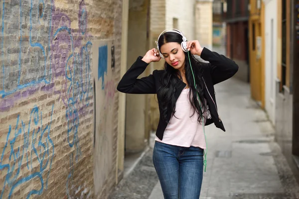 Frau im urbanen Hintergrund hört Musik mit Kopfhörern — Stockfoto