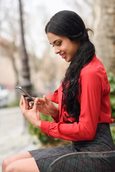 Hispanische Stewardess im urbanen Hintergrund schaut auf ihr Handy — Stockfoto