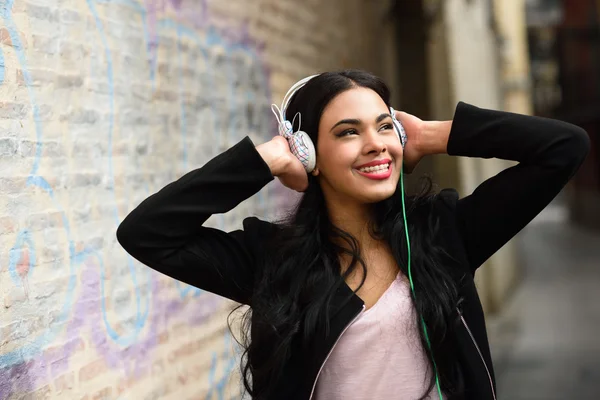Vrouw in stedelijke achtergrond muziek met een hoofdtelefoon beluisteren — Stockfoto