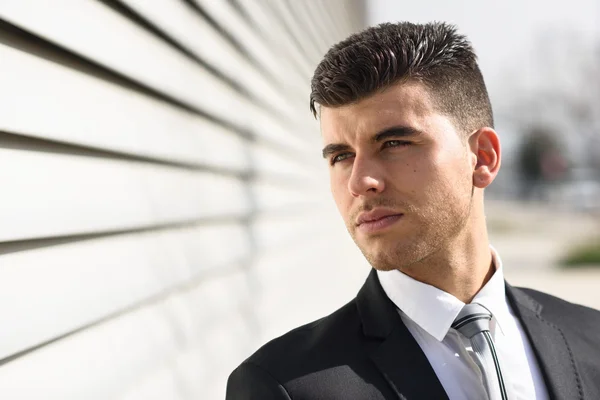 Young businessman near a office building wearing black suit — Stock Photo, Image