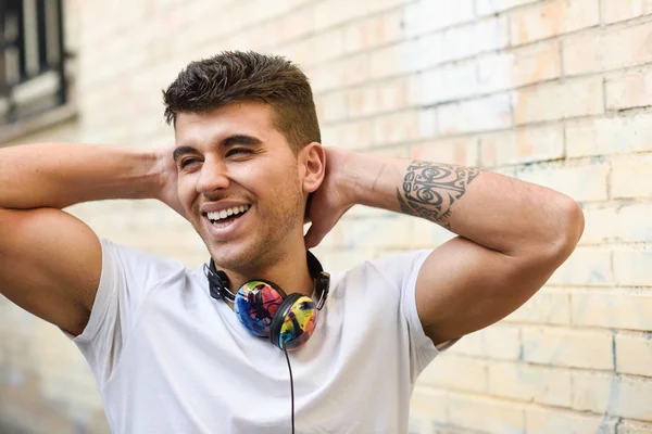 Junger Mann im urbanen Hintergrund hört Musik mit Kopfhörern — Stockfoto