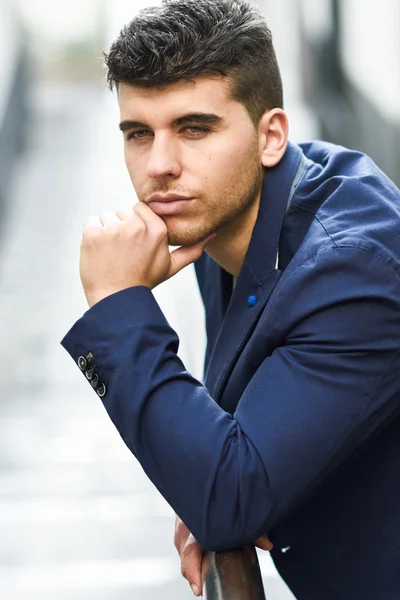 Schöner junger Mann mit blauen Augen, der in der Nähe einer Mauer posiert — Stockfoto