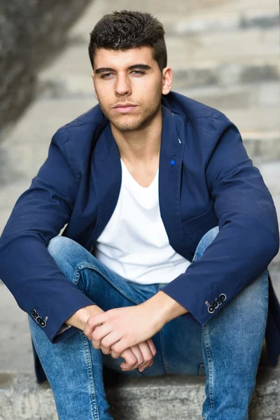 Handsome young man with blue eyes posing near a wall — Stock Photo, Image