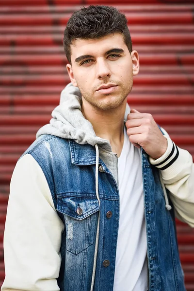 Csinos, fiatal férfi szeme kék pózol egy fal mellett — Stock Fotó