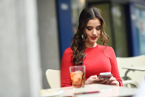 Νεαρή γυναίκα κοιτάζοντας το smartphone που κάθεται σε ένα καφέ — Φωτογραφία Αρχείου