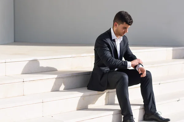 Young businessman near a office building wearing black suit — Stock Photo, Image