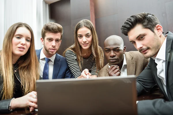 Grupo de personas multiétnicas ocupadas mirando un ordenador portátil — Foto de Stock