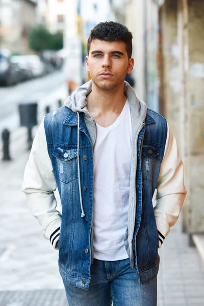 Joven guapo con ojos azules posando cerca de una pared — Foto de Stock