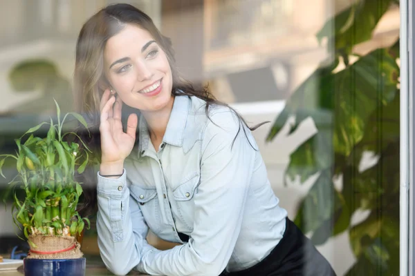 Woman sitting indoor in urban cafe looking through the window — Stock Photo, Image