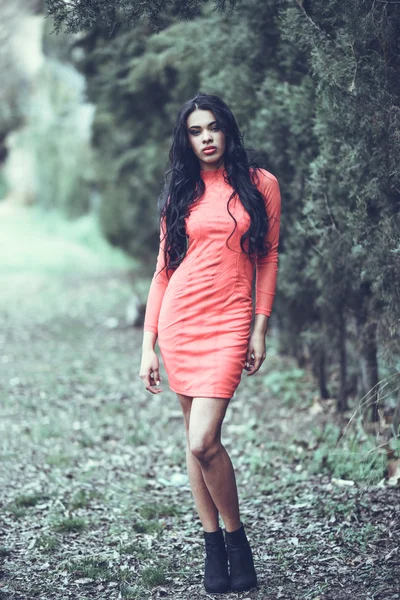 Hispanische junge Frau in orangefarbenem Kleid im Stadtpark — Stockfoto