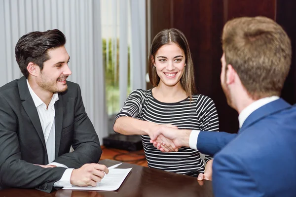 Smiling young couple shaking hands with an insurance agent — Stock Photo, Image