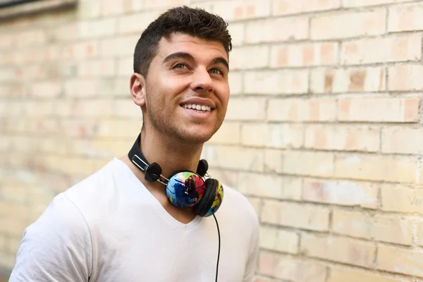 Joven en el fondo urbano escuchando música con auriculares —  Fotos de Stock