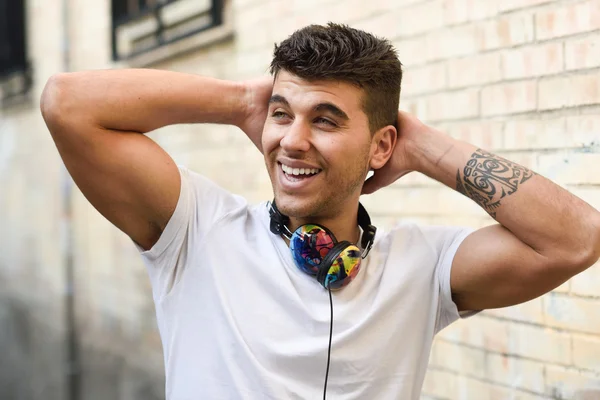 Young man in urban background listening to music with headphones — Stock Photo, Image