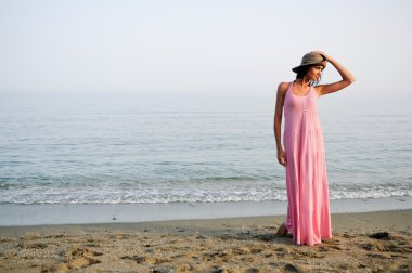 tropikal bir plajda uzun pembe elbise ile güzel bir kadın 
