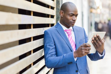 Black man wearing suit looking at his tablet computer