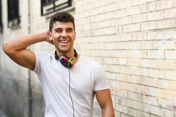 Jonge man in stedelijke achtergrond muziek met een hoofdtelefoon beluisteren — Stockfoto