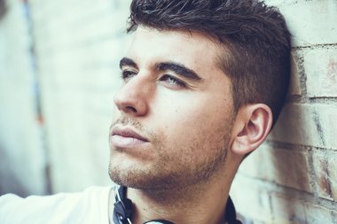 Bir duvara yakın poz mavi gözlü yakışıklı genç