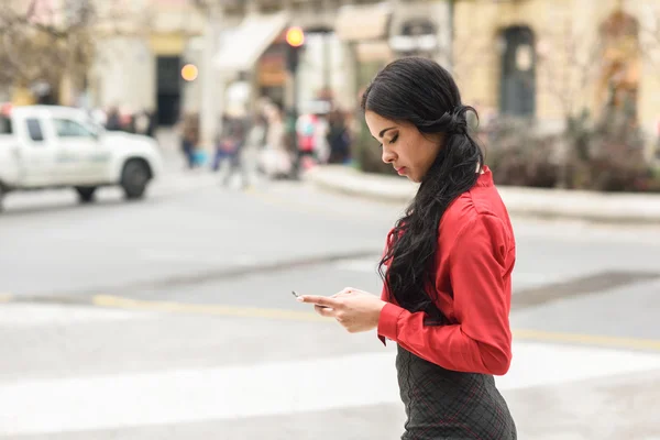 Hispanic stewardess in stedelijke achtergrond kijken naar haar mobiele ph — Stockfoto