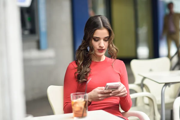 Giovane donna guardando il suo smartphone seduto in un caffè — Foto Stock