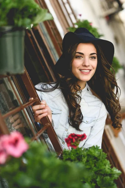 Mujer joven con sombrero en el fondo urbano con ropa casual — Foto de Stock