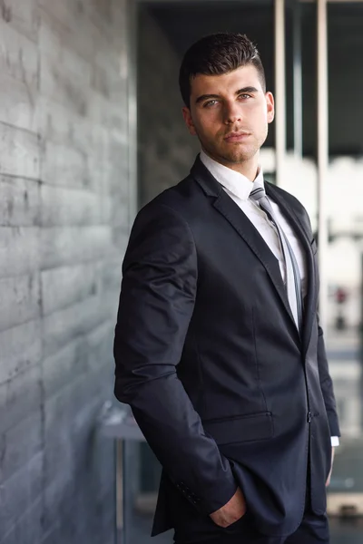 Young businessman near a office building wearing black suit — Stock Photo, Image