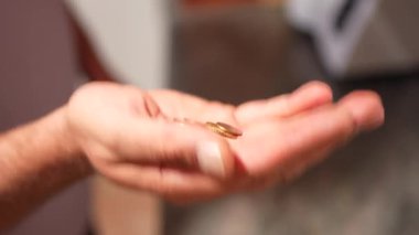 Yakın plan görüntüsü, yumuşak, bulanık bir arkaplana karşı çeşitli madeni paraları nazikçe tutan bir eli yakalar ve her bir madeni paranın yüzey ve tasarımının karmaşık dokularını ve ince detaylarını güzel bir şekilde vurgular.