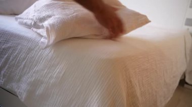 Konforlu, davetkar yatak örtüleri üzerinde güzel düzenlenmiş beyaz yatak örtüleri yumuşak yastıklar ve sıcak, zengin dokular sergileniyor. Huzurlu ve rahatlatıcı bir yatak odası atmosferi için mükemmel bir ortam yaratıyor.