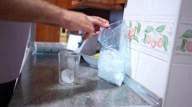 Bu hoş görüntüler serisi, zarif bir bardağı bir poşetten buzla doldurup sosyal ve aile toplantılarında su ve içki hazırlama sevincini gözler önüne seren keyifli süreci yakalar.