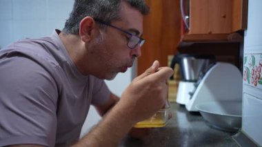 Bir adam mutfak tezgahında sıcak ve lezzetli bir yemeğin tadını çıkararak ev yemeğinin basit zevklerini tadıyor ev yemeklerinin rahatlatıcı özünü ve sıcak bir atmosferi vurguluyor.