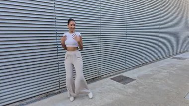 Canlı bir şehir ortamında, modaya uygun genç bir kadın kendine has tarzını sergiliyor, modaya uygun kesilmiş bir üst giysisi ve şık görünüşünü ve tavrını tamamlayan geniş bir pantolon giyiyor.