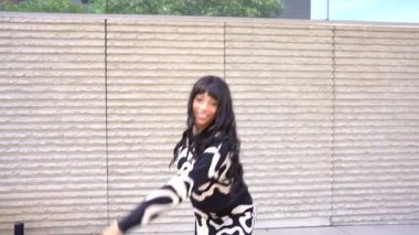 Sokakta dans eden genç siyahi kadın, çok gösterişli kıyafetler giyiyor. Gençlik hayatı ve iyi titreşimler kavramı.