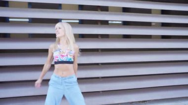 Şık, sarışın bir kadın, günışığı altında neşeli ve hayat dolu kişiliğini sergileyerek, güneşli ve güneşli bir günde mutluluk ve enerji dolu bir şekilde dans eder.