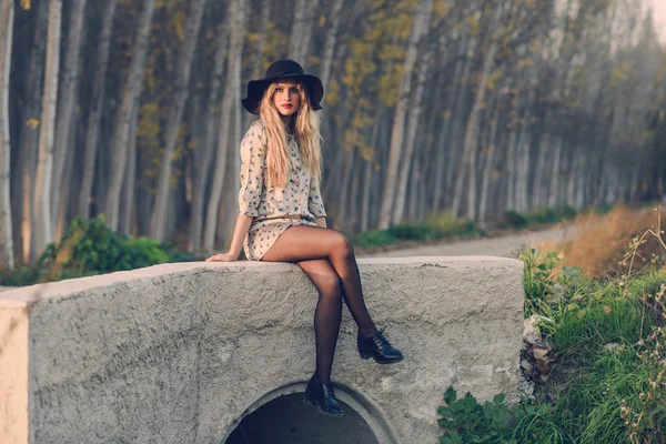 Blonde young woman with curly hair in a rural road — Stock Photo, Image