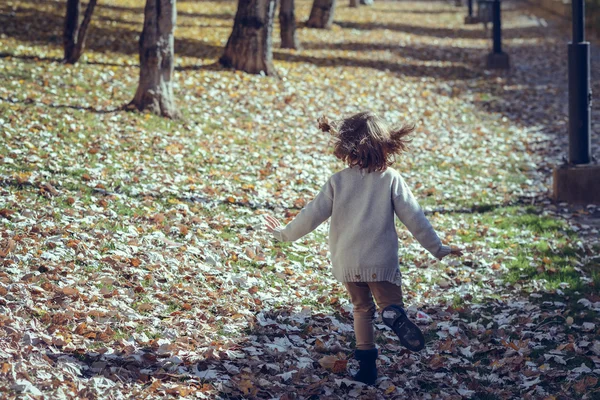 Menina brincando em um parque da cidade no outono — Fotografia de Stock