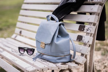 Bag, sunglasses and leather jacket on a bench