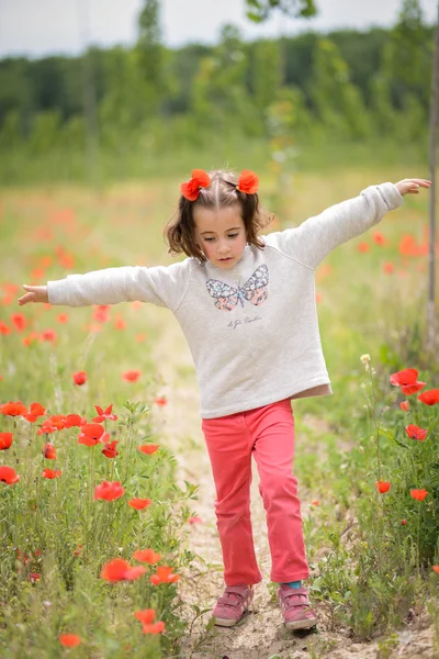 Süßes kleines Mädchen, das Spaß in einem Mohnfeld hat — Stockfoto