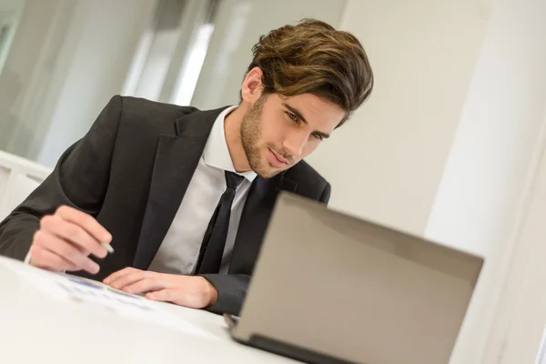 Бизнесмен сидит за ноутбуком и работает в офисе — стоковое фото