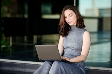 Bir modern ofis yapı içinde onun dizüstü bilgisayar kullanan iş kadını