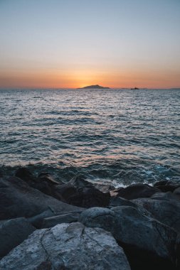 Sunset behing Ischia Island on the Sorrento Coast in Italy with Rocks and the Tyrrhenian Sea Coast clipart