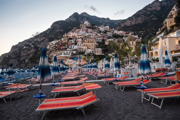 意大利波西塔诺 2020年8月24日 波西塔诺 斯皮亚吉亚海滩 有橙色海滩椅子 晚上有雨伞 可以看到村庄 — 图库照片