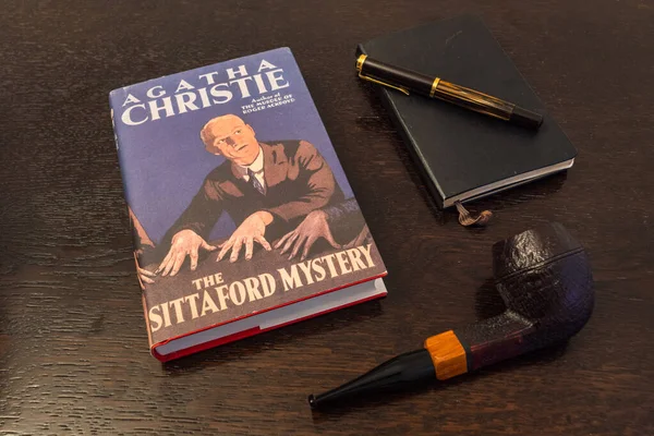 Londra, İngiltere, İngiltere - 2 Ocak 2021: Agatha Christie 'nin The Sittaford Mystery Book in a Facsimile First Edition with Tobacco Pipe, Fountian Pen and Notebook on a Table