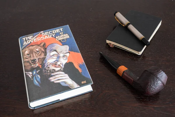 Londra, İngiltere, İngiltere - 2 Ocak 2021: Agatha Christie 'nin The Secret Adversary Book in a Facsimile First Edition with Tobacco Pipe, Fountian Pen and Notebook, a Tommy and Tuppence Story