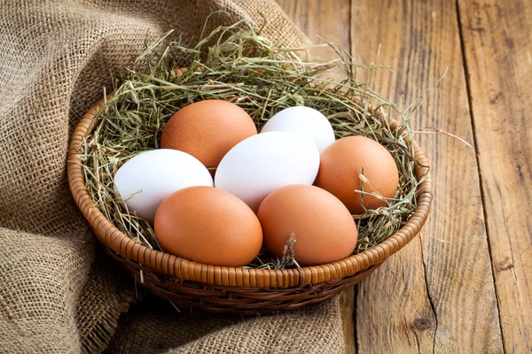 Eieren in een mand op houten achtergrond — Stockfoto