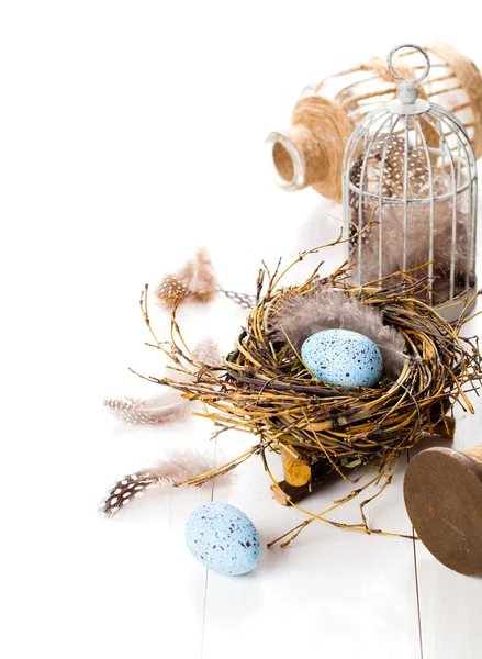 Nido de huevos de Pascua con jaula para pájaros, sobre fondo de madera blanca — Foto de Stock