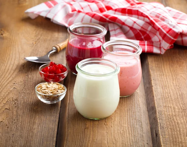 Healthy yougurt with berry in a glass jars on wooden background — Stock Photo, Image